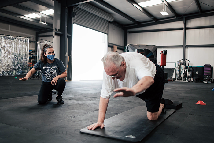 A fitness instructor helping a cancer survivor to rebuild his strength after treatment